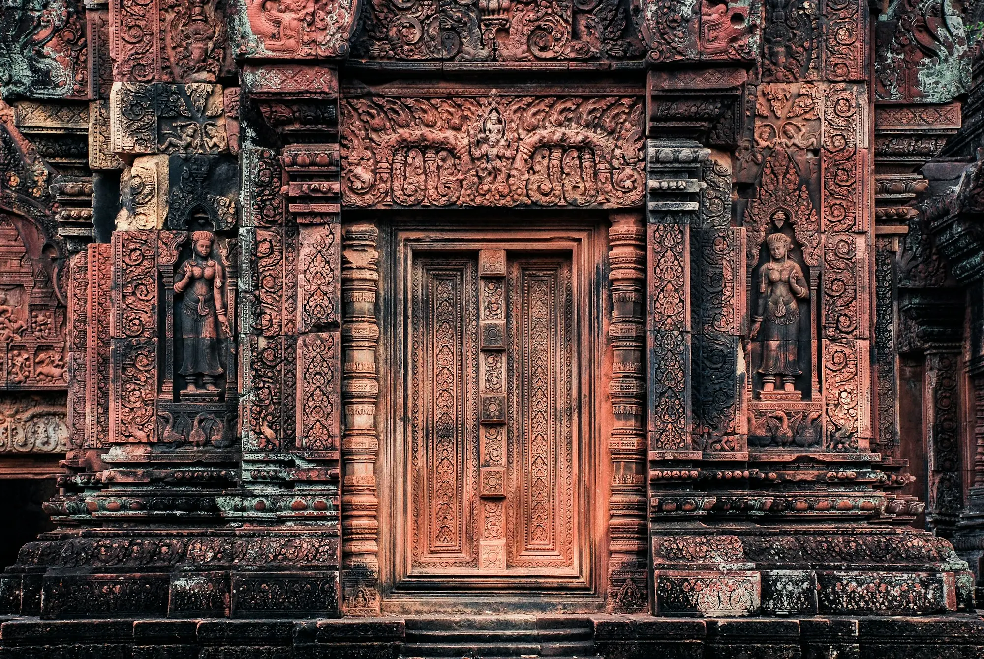 Intricately carved red sandstone doorway and devata figures at Banteay Srei