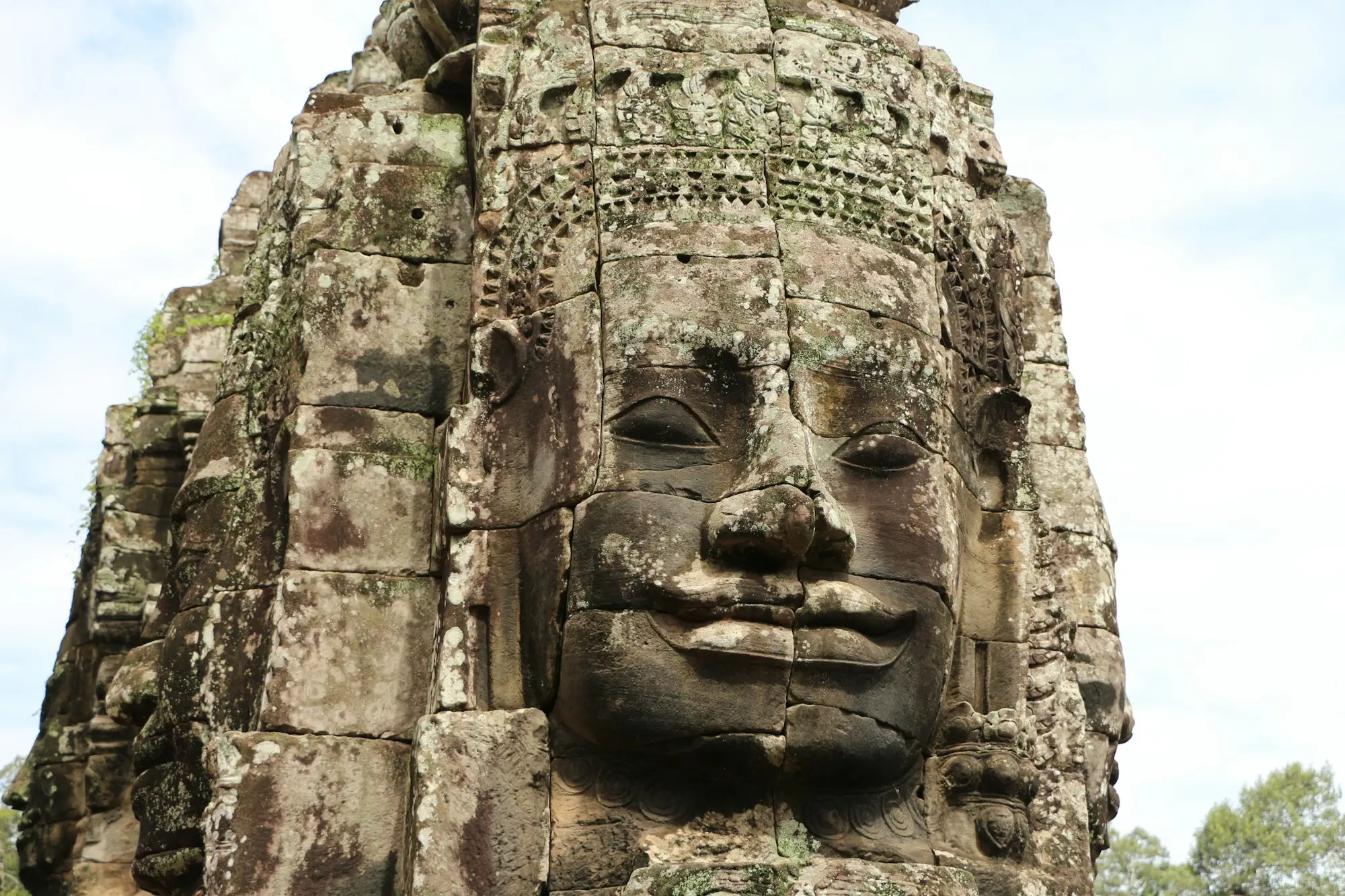 Giant smiling stone face on a tower of Bayon Temple